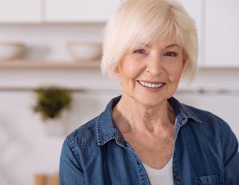 Senior woman in denim jacket smiling in kitchen