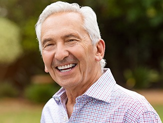 Senior man in collared shirt smiling outside