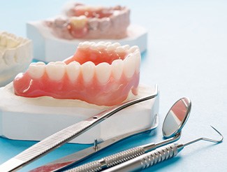 Dentures on a cast next to several dental instruments