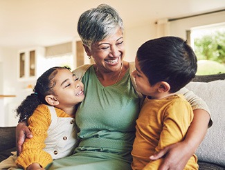 Woman in green shirt smiling down at a boy and girl wearing yellow