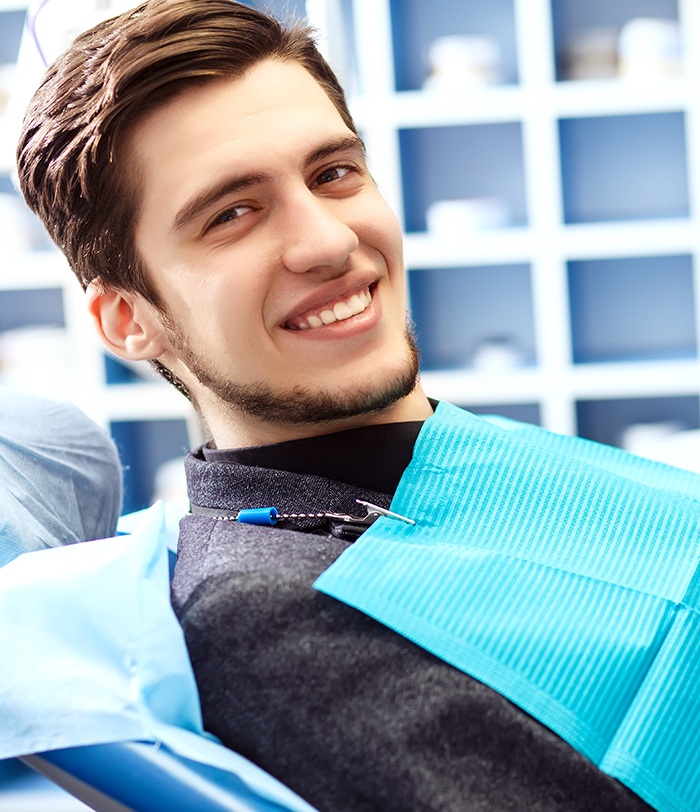 Man in dental chair lifting head and smiling