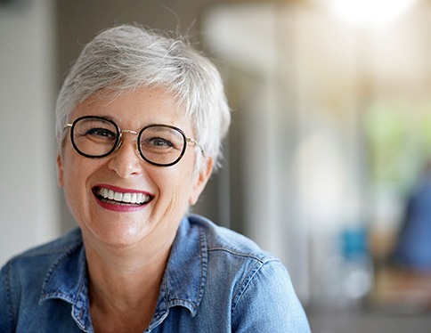 Senior woman with glasses sitting at home and smiling