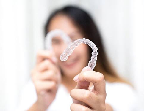Smiling patient holding clear aligners