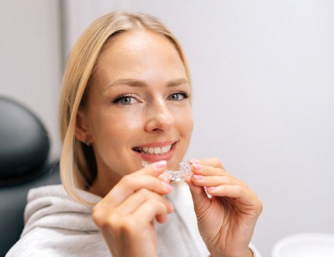 GCloseup of woman smiling while holding clear aligner