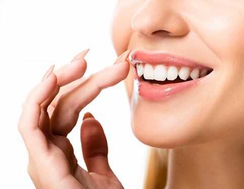 Woman delicately touching her whitened teeth